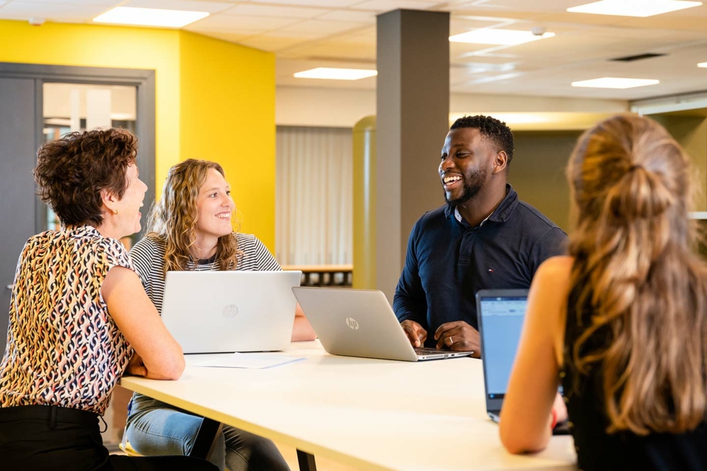 Enkele lachende medewerkers in een informeel werkoverleg.