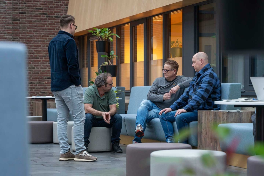 Vier mannen in gesprek in een publieke ruimte van het gemeentehuis.